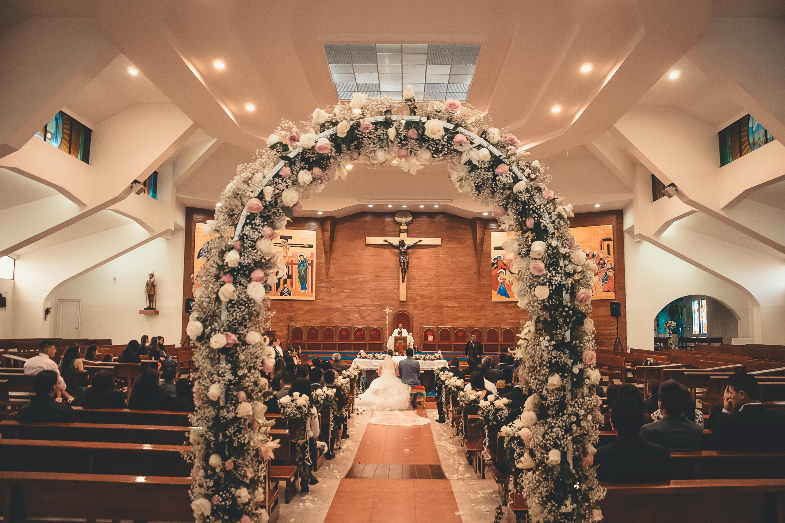 A captivating wedding ceremony inside a church featuring a floral archway and seated guests.