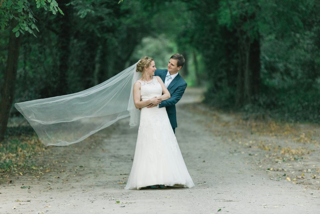 Bride and groom embrace on a forest path, capturing a magical wedding moment.